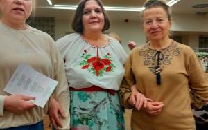 Trzy kobiety pozują do zdjęcia. Kobiety po środku i po prawej stronie mają na sobie wyszywane koszule