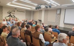 Ludzie w eleganckich strojach siedzą na krzesłach
