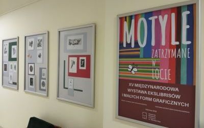 Cztery plansze wystawy ekslibrisów ujęte pod kątem. Pierwsza plansza z napisem: Motyle. Zatrzymane w locie. XV Międzynarodowa Wystawa Ekslibrisów i Małych Form Graficznych"