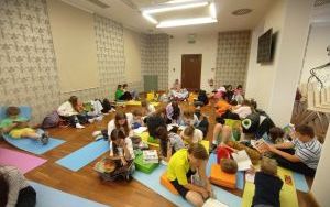 Uczniowie podstawówki siedzą na kolorowych matach i pufach, czytają książki
