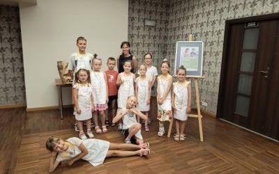 Grupa jedenaściogra dzieci pozuje do zdjęcia z dorosłą kobietą