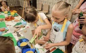 Dwie dziewczynki w wieku szkolnym stoją przy stole i nasypują do misek kaszę