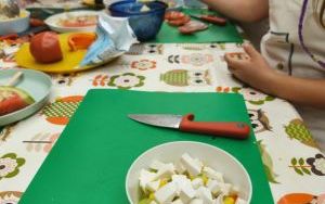 Stół z zielonymi podkładkami, na których leżą talerze i miski z owocami i warzywami