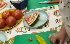 Stół z zielonymi podkładkami, na których leżą talerze i miski z owocami i warzywami
