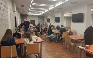 Sala ze stolikami, przy których siedzą ludzie i grają w gry planszowe