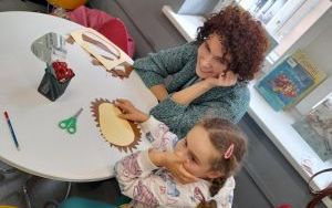 Uśmiechnięta mama siedzi wraz z dzieckiem przy okrągłym stoliku