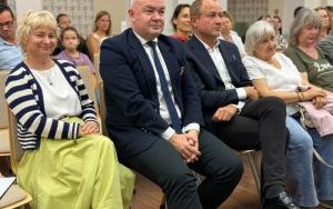 Zaproszeni goście siedzą w pierwszym rzędzie widowni i z uśmiechem obserwują przebieg spotkania.