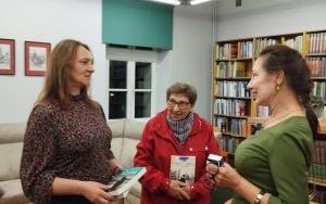 Autorka Ewa Cielesz rozmawia z dwiema uczestniczkami spotkania w bibliotece.