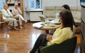 Dwie kobiety siedzą na fotelach. Przed nimi publiczość